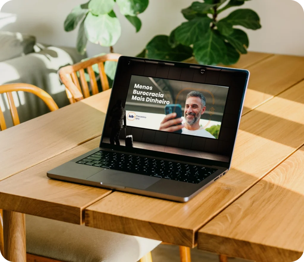 Laptop exibindo texto "Menos Burocracia Mais Dinheiro" e rosto sorrindo. LCB Assessoria DNA.