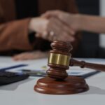 Martelo de juiz e aperto de mãos simbolizando acordo legal